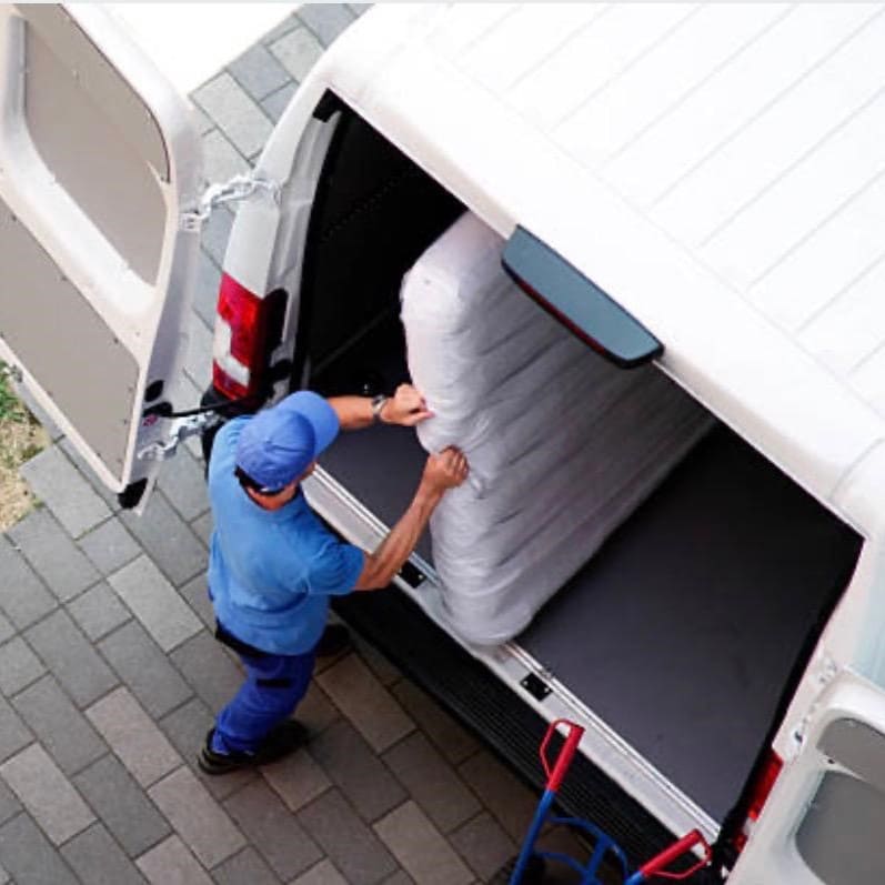 Professionelle Tragehilfe beim Beladen eines weißen Transporters mit schweren Gegenständen.