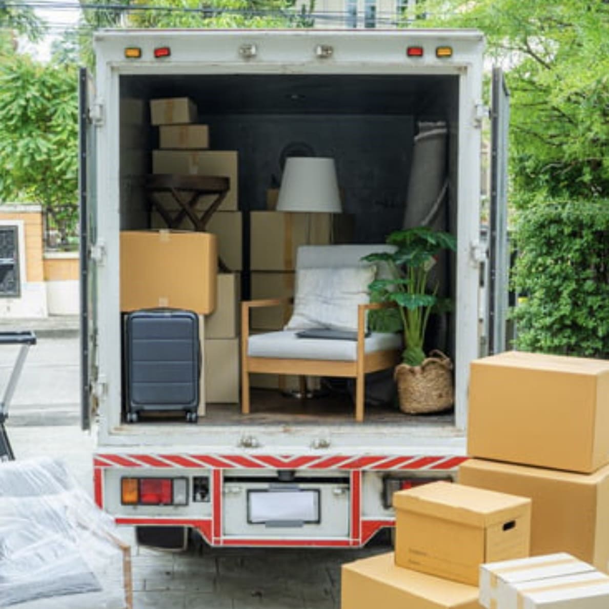 Professionelle Umzugshilfe: Beladener Umzugswagen mit Kartons, Sessel und Stehlampe.